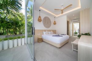 ラワイビーチにあるTropical Brand New 4BR Pool Villa Mina, just 5 min Drive from Naiharnのベッドルーム1室(ベッド1台付)、植物のあるバルコニーが備わります。 +22枚の写真