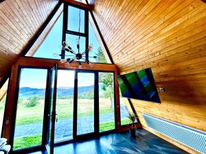 an attic room with a large window and a chandelier at Nemes Chalet A Frame in Văleni