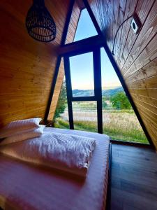 a bed in a room with a large window at Nemes Chalet A Frame in Văleni +75 photos