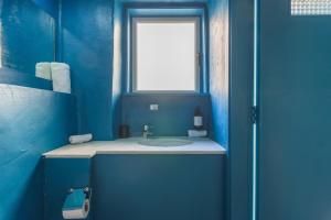a blue bathroom with a sink and a window at SAYA La Villa in Mar Mikhael in Beirut