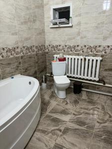 a bathroom with a toilet and a bath tub at Гостевой дом in Aralʼsk +41 photos