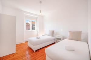 une chambre blanche avec deux lits et une fenêtre dans l'établissement GuestReady - City views and comfort in Arroios, à Lisbonne