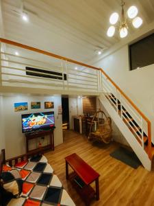 a living room with a staircase with a television and a couch at The River House - Govantes Guesthouse in Vigan