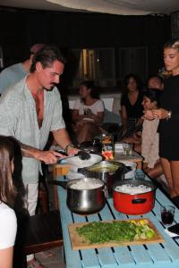 a man preparing food on a table with people at Tamaran House in Las Palmas de Gran Canaria