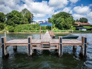 a wooden dock with an umbrella on the water at Stella Maris in Svendborg