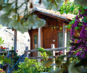 a wooden cabin with flowers in front of it at Agora Pansiyon in Kapıkırı
