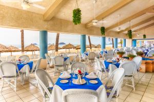 a restaurant with blue tables and white chairs at Posada Real Ixtapa in Ixtapa