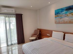 Una habitación de hotel con una cama y una ventana. en Gemma Hotel Balige, en Balige