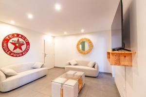 a living room with two couches and a flat screen tv at Le Gîte de la Route 999 - Belle maison de campagne in Montlaur