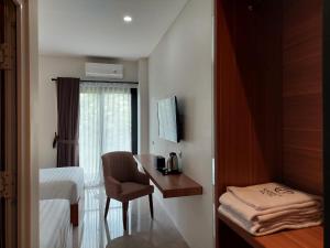 a hotel room with a desk and a bed and a window at Gemma Hotel Balige in Balige