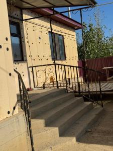 a house with stairs in front of a building at Гостевой дом in Aralʼsk