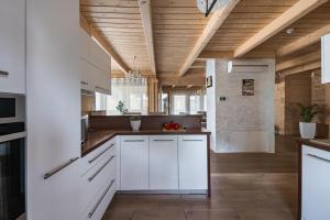 a kitchen with white cabinets and a wooden ceiling at Pienińska Przystań dom w Szczawnicy in Szczawnica