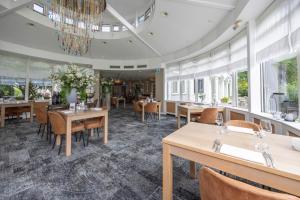 a dining room with tables and chairs and a chandelier at Fletcher Hotel Restaurant De Witte Raaf in Noordwijk