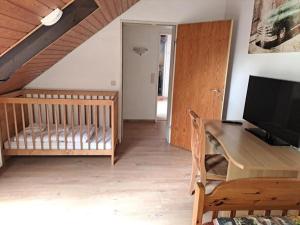 a living room with a desk with a television and a crib at Ferienwohnung Heckenäcker in Ortenberg