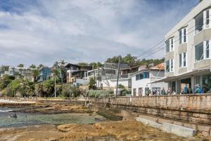 a group of people standing on a wall near the water at Luxury Manly Oceanfront Getaway in Sydney