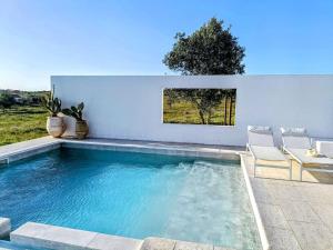 a swimming pool with two chairs next to a house at Casa dos Bonitos in Santa Susana
