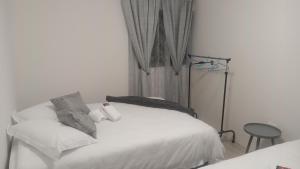 a bedroom with a white bed and a window at Shalom Self Catering in Lüderitz +3 photos