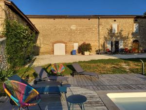 a patio with a table and chairs and a building at La Maison du Pouget in Fénols