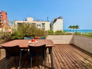 a wooden table and chairs on a deck with the ocean at Increíble casa frente al mar , planta baja in Torredembarra