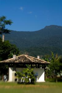 a house with a roof with a mountain in the background at Costabela Apart Hotel e Pousada in Ilhabela