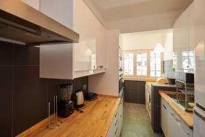a kitchen with white cabinets and a wooden counter top at Central Oasis Apartment in Cascais