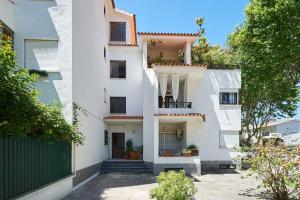 a white building with a balcony and a gate at Central Oasis Apartment in Cascais