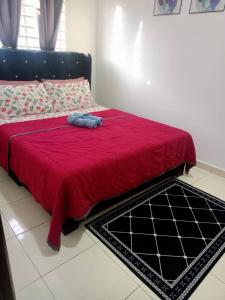 a red bed with a redspread and a blue object on it at Ammara Homestay PD in Kampong Tanah Merah +4 photos