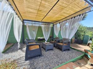 a patio with chairs and curtains and a table at Finca Esther in Las Palmas de Gran Canaria