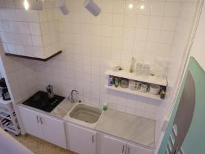 a small white tiled kitchen with a sink at Casa al Castillo - charming & authentic townhouse - terrace with stunning castle views in Cullera +55 photos