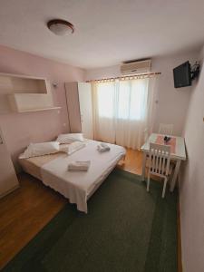 a bedroom with a bed and a table and a chair at Apartman Lampić with beautiful sea view in Podgora