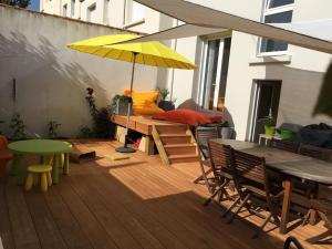 eine Terrasse mit einem Tisch und einem gelben Sonnenschirm in der Unterkunft À 2 pas de plage et commerces, jardin & parking in Les Sables-dʼOlonne