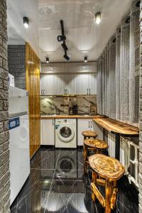 a kitchen with a washing machine and two stools at Квартира на Арбате 1 ком in Shymkent