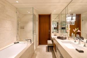 a bathroom with two sinks and a bath tub at The Leela Hyderabad Banjara Hills in Hyderabad