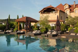 a swimming pool with umbrellas and chairs next to a building at Domaine de la Klauss & Spa, Restaurant Gastronomique Le K in Montenach
