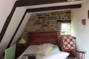 a bedroom with a bed and a stone wall at grange cavanet in Goulles