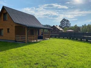 a wooden cabin in a field next to a fence at Domki za Lasem in Radawa