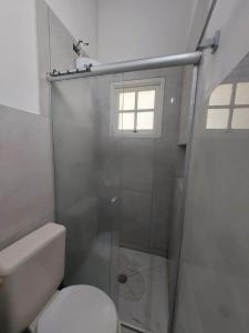 a bathroom with a shower with a toilet and a window at Flat Maresias in São Sebastião