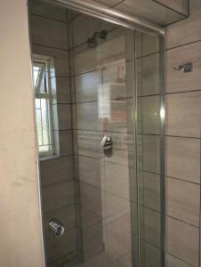 a shower with a glass door in a bathroom at Feet Up Cottage in Somerset West