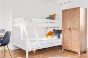 a white bunk bed with a ladder next to a wooden cabinet at Woodfield Cottage Skåne in Vollsjö