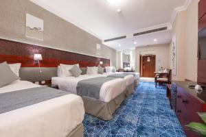 a hotel room with four beds and a blue carpet at Shaza Regency Plaza Al Madinah in Al Madinah +27 photos
