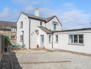 a white house with a driveway in front of it at 1 Tyn Y Gongl Cottage in Beaumaris