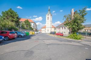 a church with a clock tower in a parking lot at BartApart in Kutná Hora