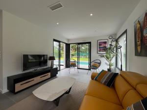 a living room with a couch and a tv at Villas-des-oyats - Arena - 8 personnes climatisée piscine chauffée in Seignosse