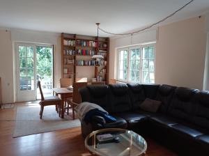 a living room with a black couch and a table at Privatzimmer im Landhaus mit großem Garten und Parkplatz in Reckershausen