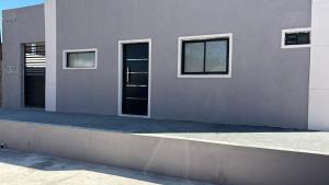 a white house with two windows and a sidewalk at La Martina in Esquina