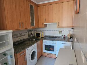 a kitchen with wooden cabinets and a washing machine at Apartamento Miravalles in Muros de Nalón +6 photos