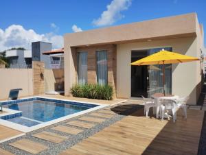 a villa with a swimming pool and a yellow umbrella at Casa Jacuípe in Camaçari