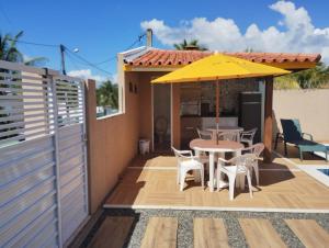a patio with a table and a yellow umbrella at Casa Jacuípe in Camaçari