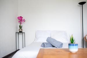 a white bed with two pillows and a vase of flowers at T2 Rangueil - Terrasse + 2 Parkings - 4 personnes in Toulouse +6 photos