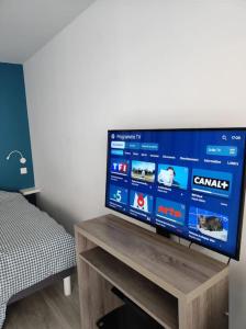 einen Flachbild-TV auf einem Holztisch in der Unterkunft Appart 3 pers piscine parking coeur de ville in Grenoble